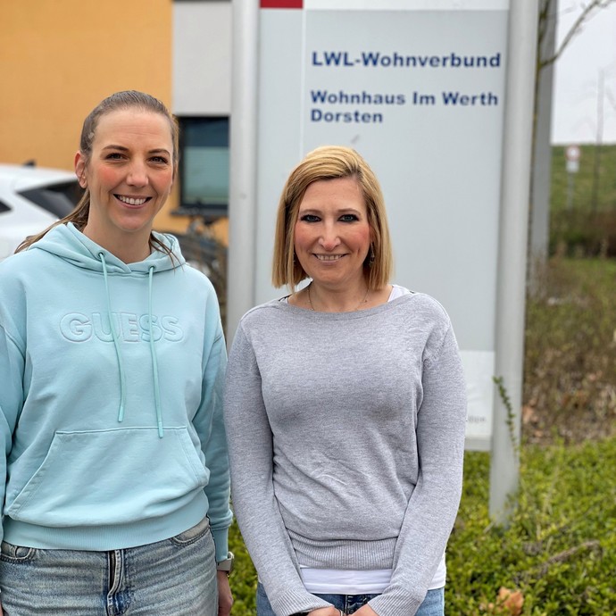 Zwei Frauen stehen nebeneinander und lächeln (vergrößerte Bildansicht wird geöffnet)
