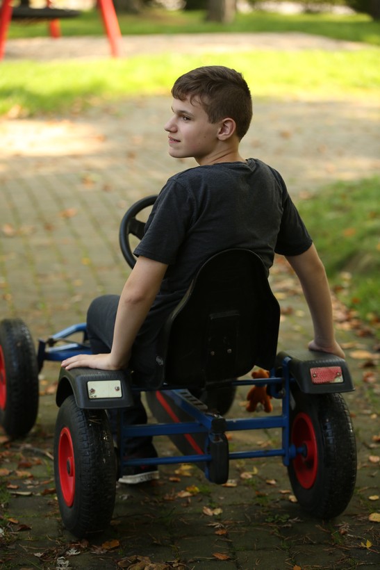 Ein Junge sitzt auf einem roten Kettcar und schaut über seine linke Schulter. Ein Junge sitzt auf einem roten Kettcar und schaut über seine linke Schulter.
